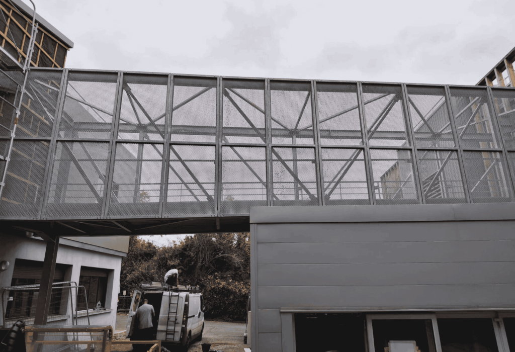 Passerelle métallique grillagée reliant deux bâtiments, structure acier fabriquée et posée par A2SI à Bidos (64)